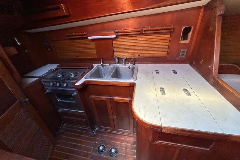 Slide: The Image of 1983 Morgan 45 Catalina yacht kitchen with stove, sink, and wooden cabinetry. - 212