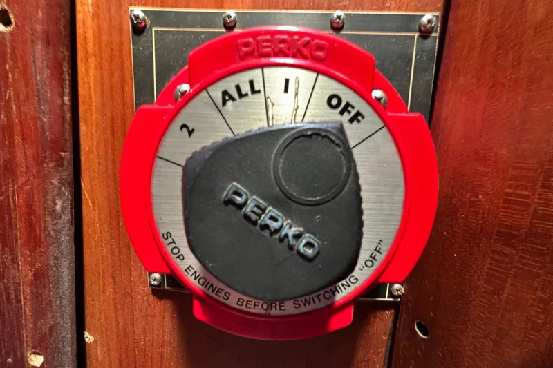 Slide: The Image of Red Perko battery switch on 1983 Morgan 45 Catalina boat, mounted on wooden panel. - 218