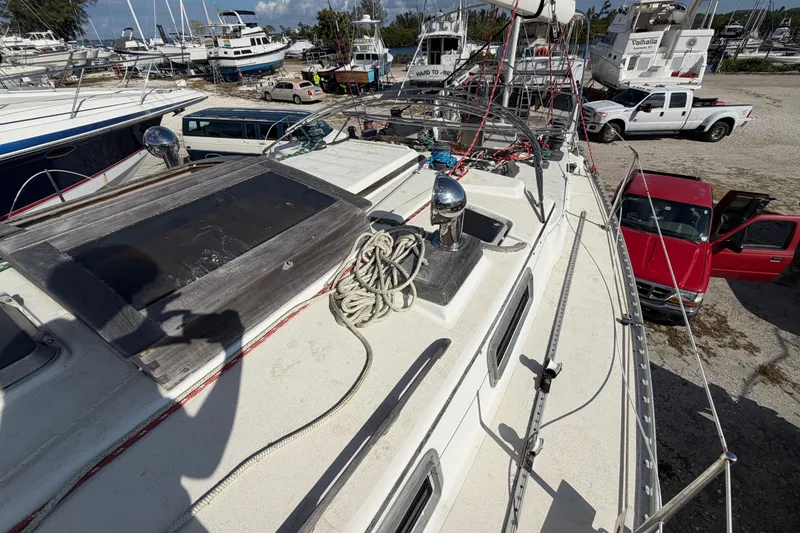 Slide: The Image of 1983 Morgan Catilina sailboat on deck, surrounded by parked vehicles and other boats. - 77