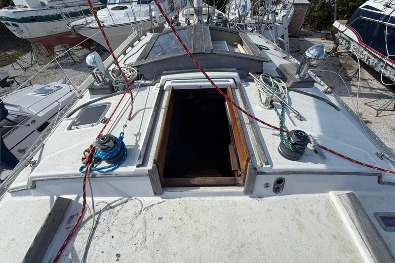 Slide: The Image of 1983 Morgan Catilina sailboat deck with open hatch and rigging, docked among other boats. - 80