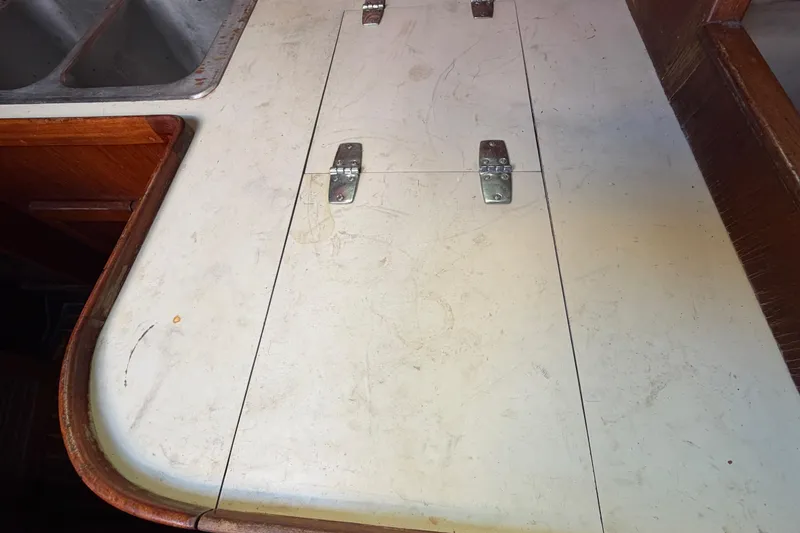 Slide: The Image of 1983 Morgan Catilina boat interior with white countertop and metal hinges. - 84