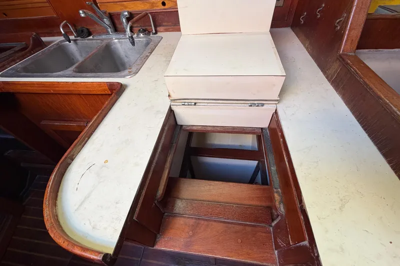 Slide: The Image of 1983 Morgan Catilina yacht kitchen with wooden cabinetry, dual sinks, and hidden storage compartment. - 85