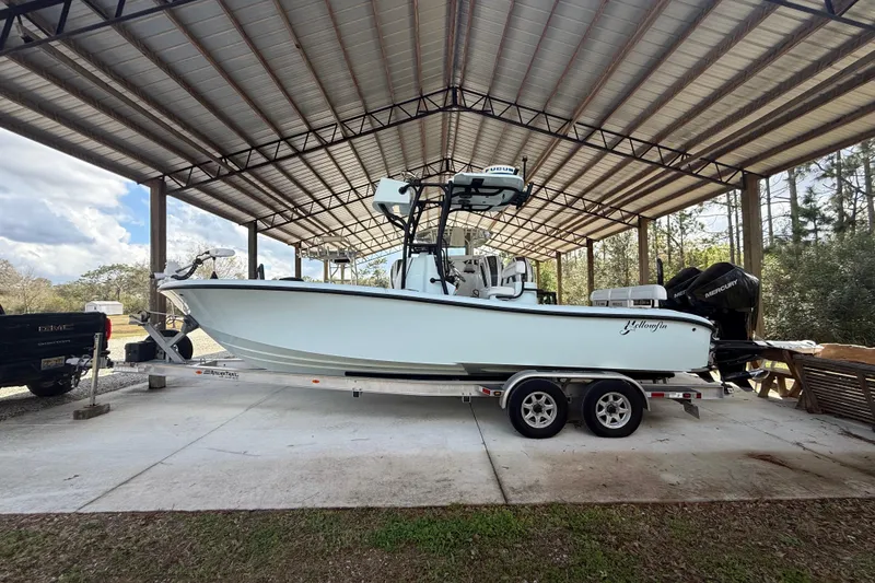 The Image of 2021 Yellowfin 26 Hybrid boat on trailer under metal canopy. - 0