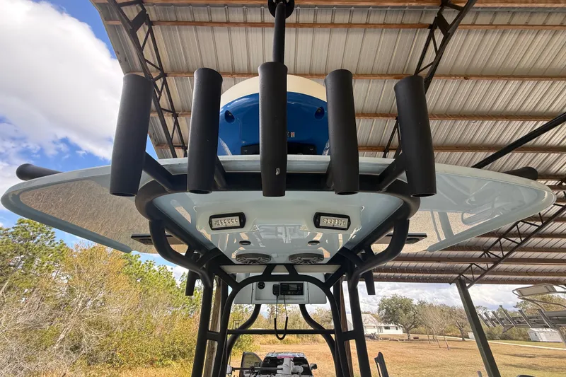 Slide: The Image of 2021 Yellowfin 26 Hybrid boat under a metal roof, featuring rod holders and LED lights. - 33