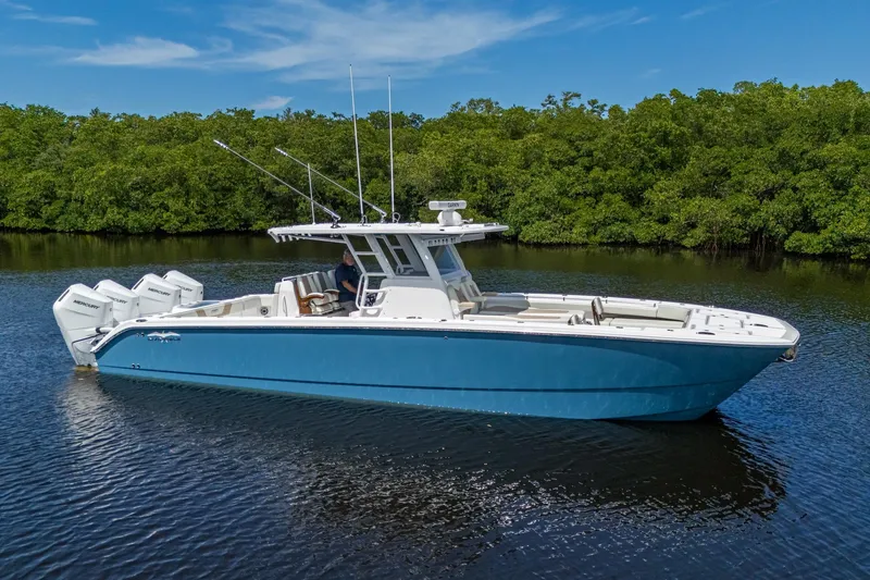 The Image of 2025 Invincible 37 Catamaran in blue, cruising on calm water with lush greenery background. - 1