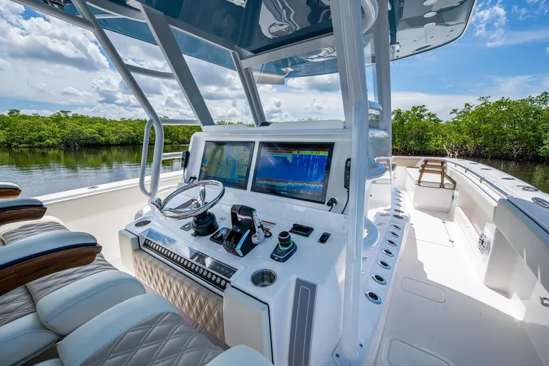 Slide: The Image of 2025 Invincible 37 Catamaran cockpit with advanced navigation system, luxurious seating, and scenic waterway view. - 10