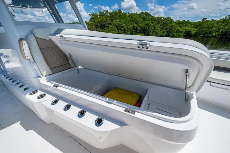 Slide: The Image of 2025 Invincible 37 Catamaran with open storage compartment, luxurious seating, and scenic background. - 23