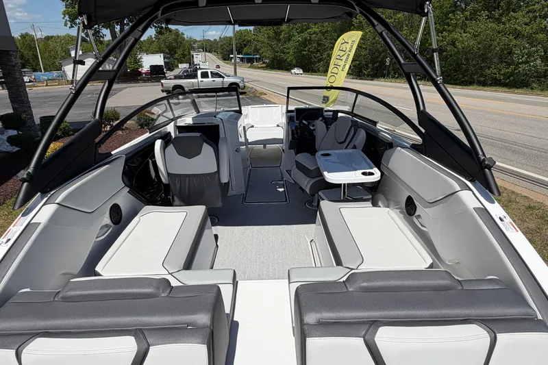 Slide: The Image of 2026 Yamaha Boats AR250 interior with seating, table, and steering wheel, parked near a road. - 15