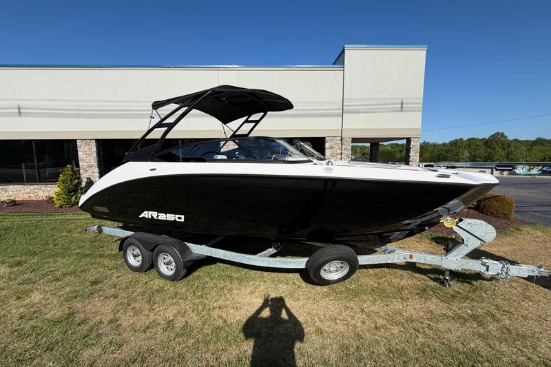 The Image of 2026 Yamaha Boats AR250 on trailer, black and white design, parked outdoors. - 0