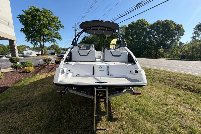 Slide: The Image of 2026 Yamaha Boats AR250 on trailer, rear view, parked on grass near road. - 9