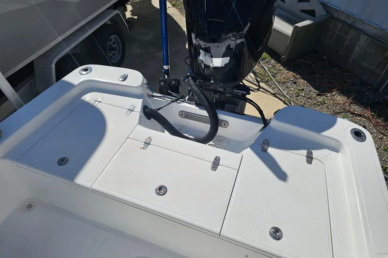 Slide: The Image of 2013 BlackJack 224 boat deck with motor, featuring storage compartments and clean design. - 14