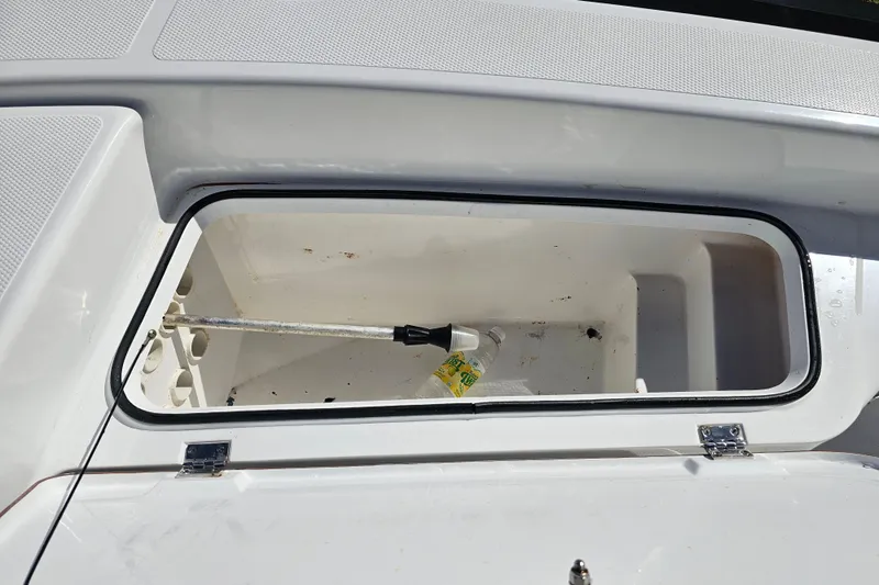 Slide: The Image of Open storage compartment on 2013 BlackJack 224 boat with cleaning supplies inside. - 19