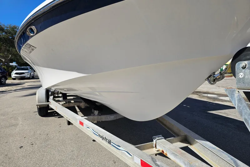 Slide: The Image of 2013 BlackJack 224 boat on trailer, featuring a T-top and outboard motor. - 2