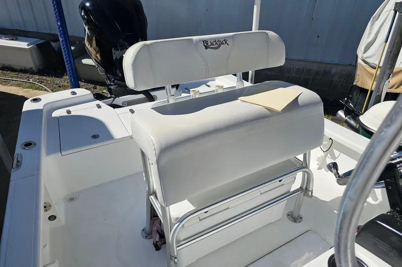 Slide: The Image of 2013 BlackJack 224 boat interior with white seating and engine in sunlight. - 23