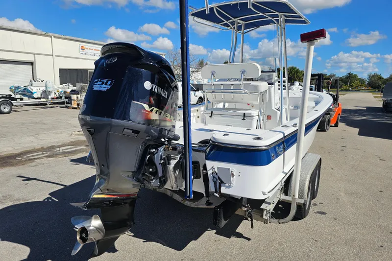 Slide: The Image of 2013 BlackJack 224 boat on trailer, parked outdoors under a clear blue sky. - 5