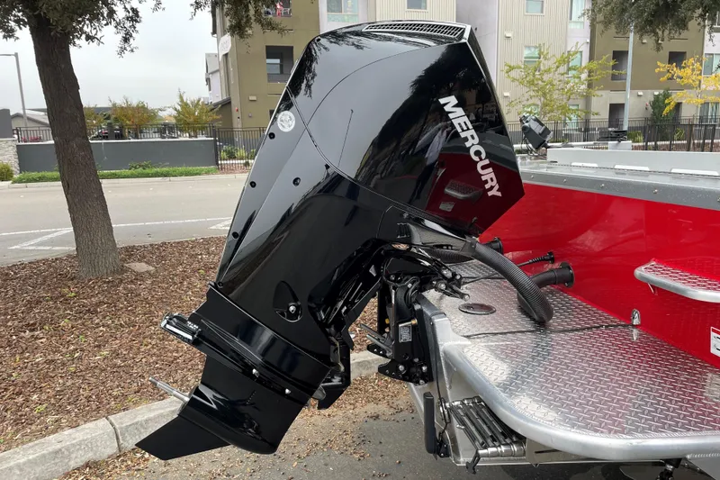 Slide: The Image of 2024 Spartan 200 Astoria boat with Mercury outboard motor, parked outdoors. - 18