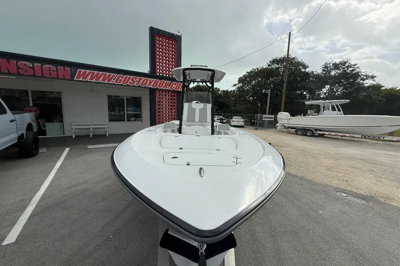Slide: The Image of 2026 Contender 26 Bay boat at dealership, front view with trees in background. - 8