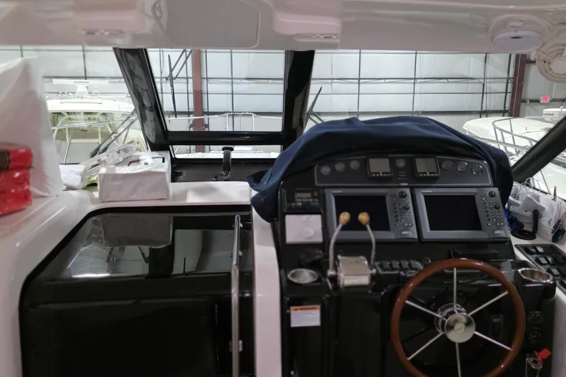 Slide: The Image of 2005 Tiara Yachts 3600 Sovran helm with navigation equipment and steering wheel in a marina setting. - 19