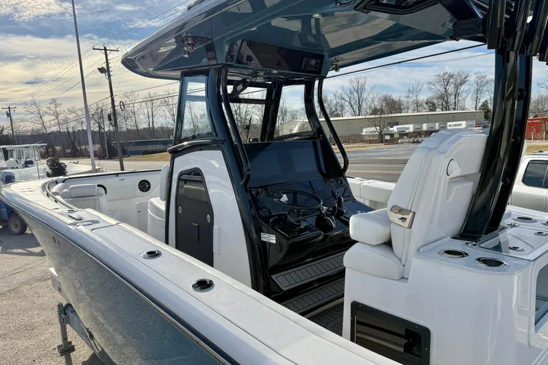 Slide: The Image of 2026 Tidewater 302 CC Adventure boat interior with helm and seating, parked outdoors. - 36