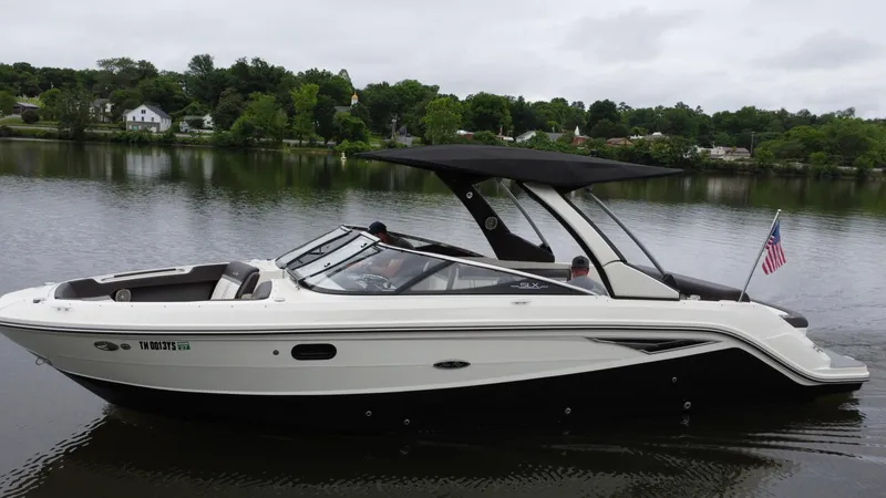 Slide: The Image of 2017 Sea Ray SLX 280 boat cruising on a calm lake with lush green shoreline. - 5