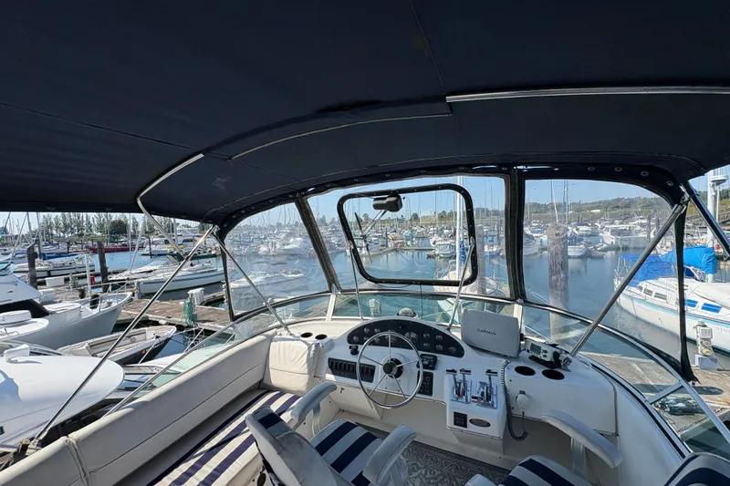 Slide: The Image of 1988 Bayliner 3587 Motoryacht helm with marina view, featuring striped seating and navigation equipment. - 30