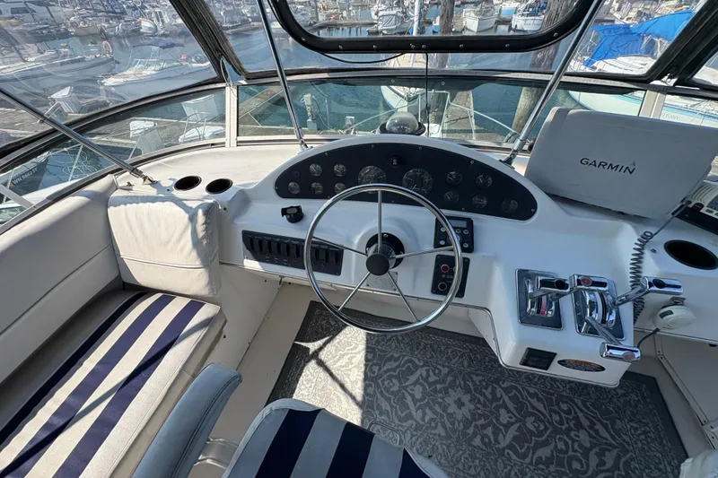 Slide: The Image of 1988 Bayliner 3587 Motoryacht helm with Garmin navigation, striped seating, and marina view. - 31