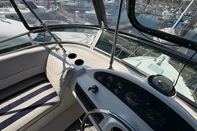 Slide: The Image of 1988 Bayliner 3587 Motoryacht helm with marina view, featuring navigation instruments and seating. - 37