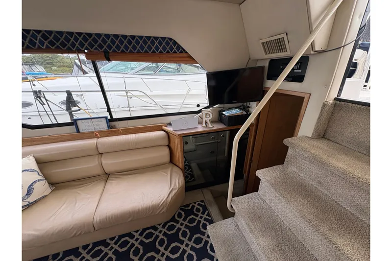 Slide: The Image of 1988 Bayliner 3587 Motoryacht interior with beige seating, TV, and carpeted stairs. - 51