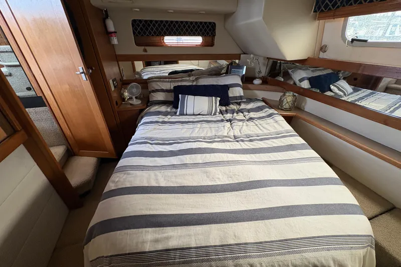 Slide: The Image of 1988 Bayliner 3587 Motoryacht bedroom with striped bedding and wooden interior. - 89