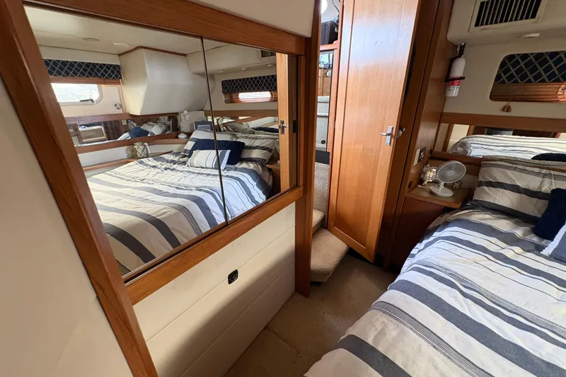 Slide: The Image of 1988 Bayliner 3587 Motoryacht interior with striped bedding and wooden cabinetry. - 96