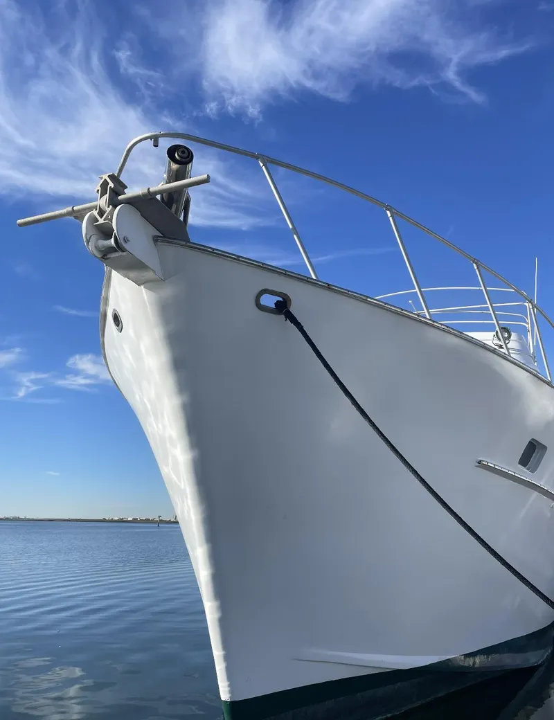 Slide: The Image of 1977 Huckins Motor Yacht with sleek white hull against a clear blue sky. - 1