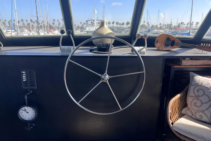 Slide: The Image of 1977 Huckins Motor Yacht helm with steering wheel, nautical decor, and marina view. - 22