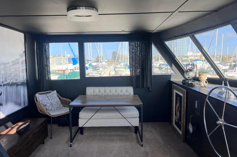 Slide: The Image of Interior of a 1977 Huckins Motor Yacht with marina view, featuring elegant seating and decor. - 23