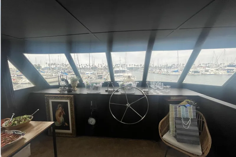 Slide: The Image of Interior view of a 1977 Huckins Motor Yacht helm with marina in the background. - 24