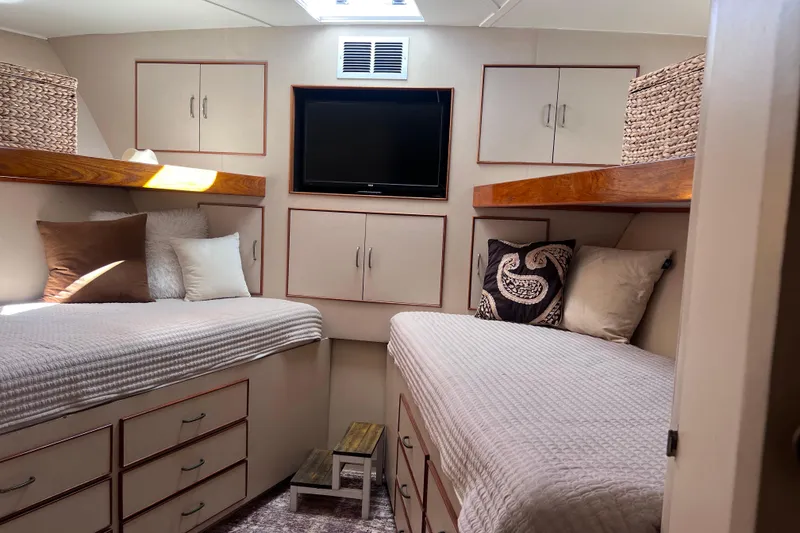 Slide: The Image of 1977 Huckins Motor Yacht cabin with twin beds, TV, and storage cabinets. - 26