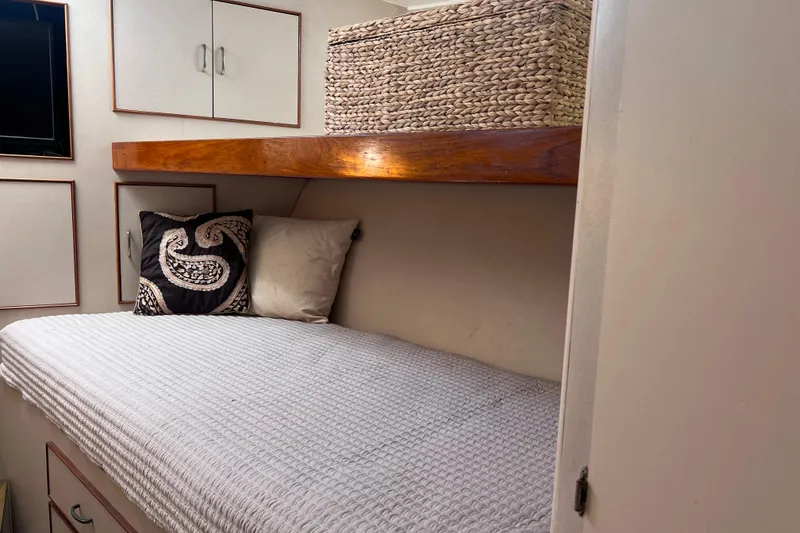 Slide: The Image of Cozy cabin interior of 1977 Huckins Motor Yacht with bed, pillows, and storage basket. - 28