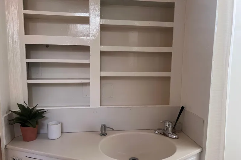 Slide: The Image of 1977 Huckins Motor Yacht bathroom with sink, shelves, plant, and toiletries. - 31