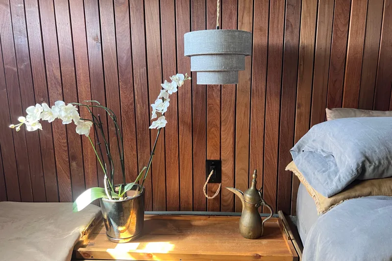 Slide: The Image of Wood-paneled yacht interior with orchid, vintage lamp, and cozy bedding, Huckins Motor Yacht 1977. - 43