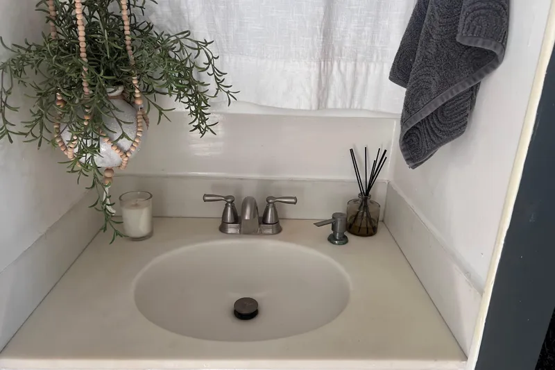 Slide: The Image of Small bathroom sink with plants, candle, and towel on a 1977 Huckins Motor Yacht. - 47