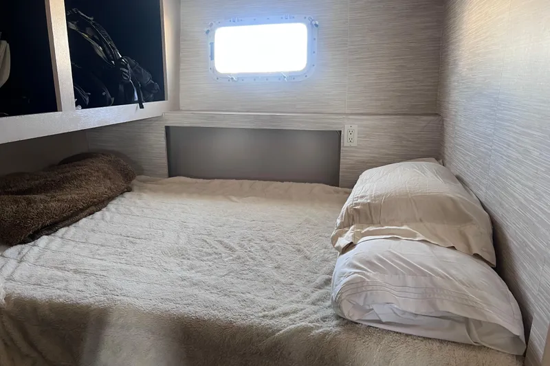 Slide: The Image of Cozy cabin interior of a 1977 Huckins Motor Yacht with a bed and window. - 48