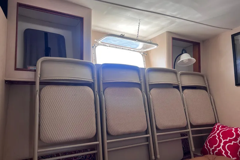 Slide: The Image of 1977 Huckins Motor Yacht interior with folding chairs and a window. - 52