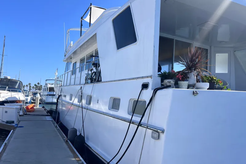 Slide: The Image of 1977 Huckins Motor Yacht docked, featuring potted plants and a bicycle on deck. - 6