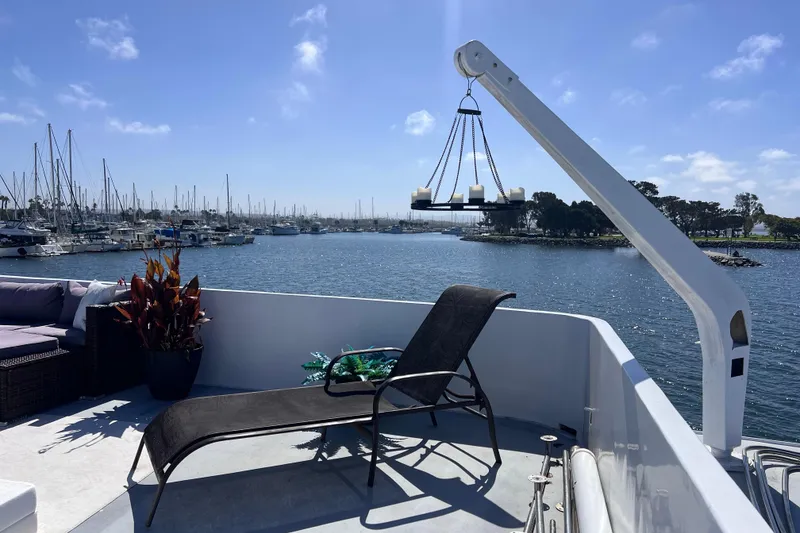 Slide: The Image of 1977 Huckins Motor Yacht deck with lounge chair, candle chandelier, and marina view. - 64