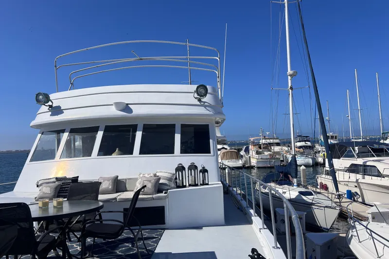 Slide: The Image of 1977 Huckins Motor Yacht docked, featuring spacious deck with seating and dining area. - 65