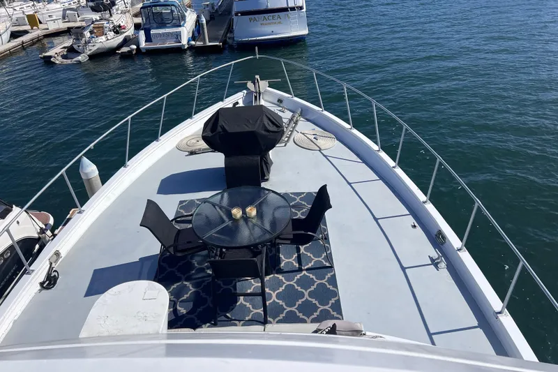 Slide: The Image of 1977 Huckins Motor Yacht deck with table, chairs, and grill, docked at marina. - 68