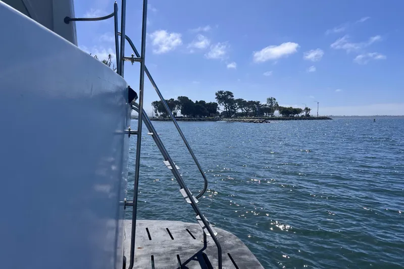 Slide: The Image of 1977 Huckins Motor Yacht on serene water with distant shoreline view. - 69