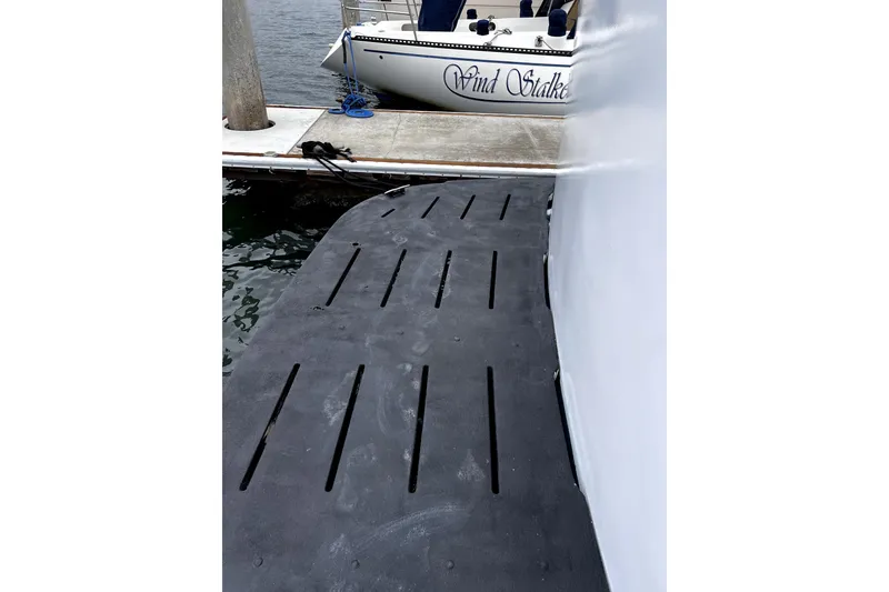 Slide: The Image of 1977 Huckins Motor Yacht docked beside a pier with a visible swim platform. - 70