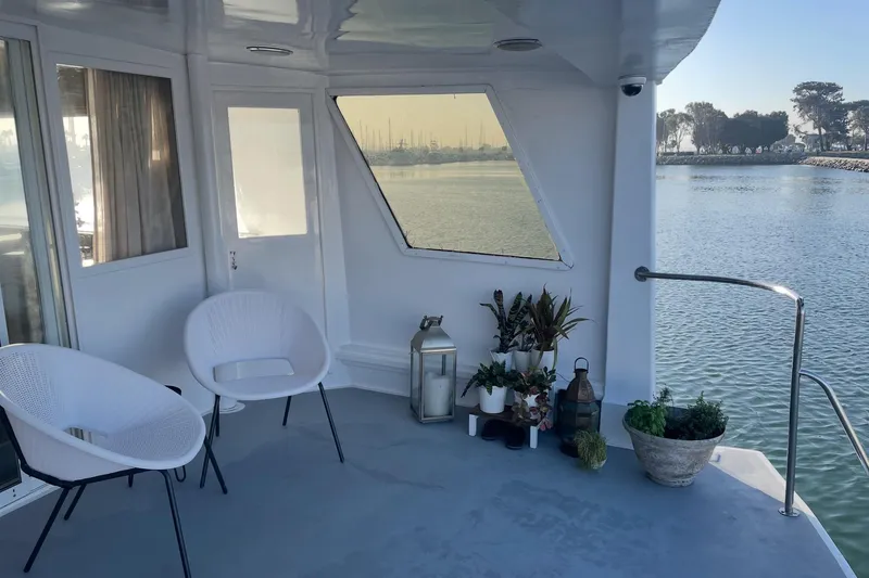 Slide: The Image of 1977 Huckins Motor Yacht deck with chairs, plants, and waterfront view. - 8