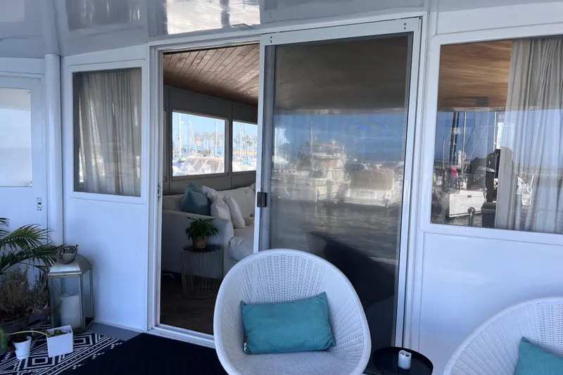 Slide: The Image of 1977 Huckins Motor Yacht interior with wicker chairs, cushions, and marina view. - 9