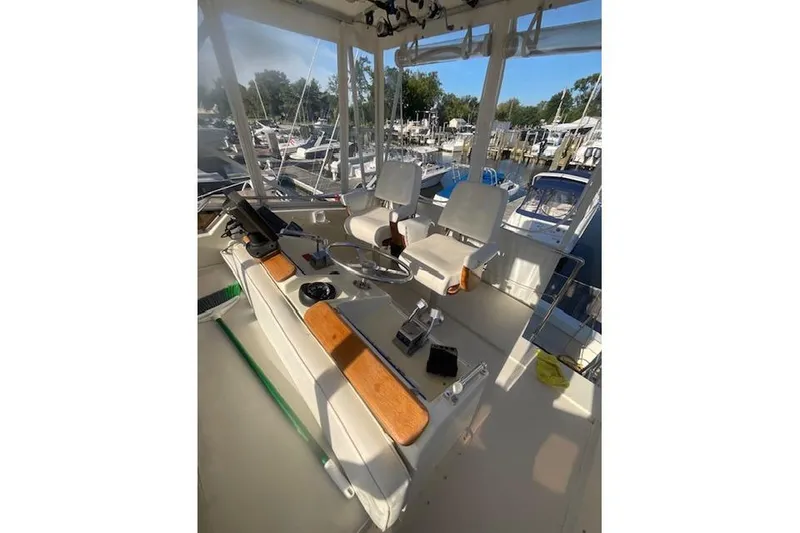 Slide: The Image of 1985 Hatteras 36 Convertible boat cockpit with helm, chairs, and marina view. - 3